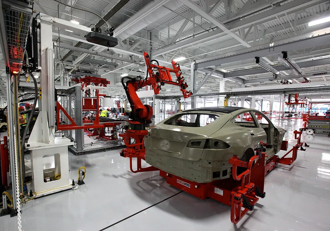 Fabrieksrondleiding bij Tesla: een medewerker installeert het gelaagde glazen dak op de productielijn
